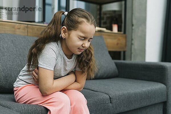 Kleines Mädchen hält Hände ihren Bauch leiden unter Schmerzen