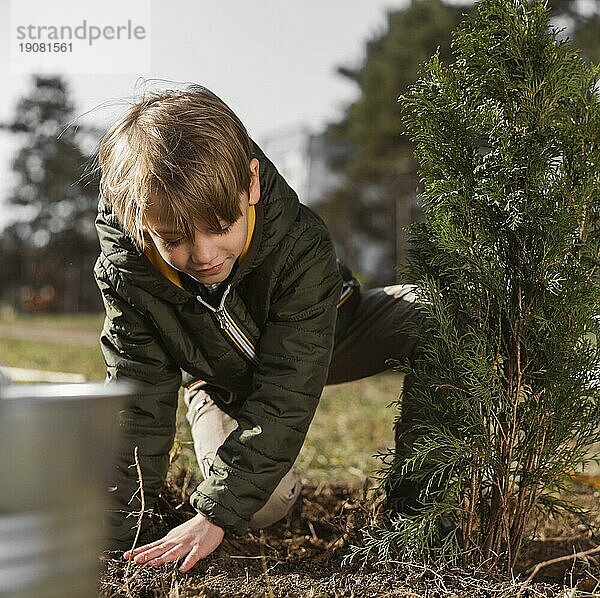 Vorderansicht junger Junge pflanzt Baum im Freien