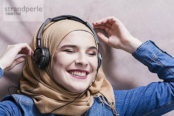 Muslimische Frau hört Musik über Kopfhörer