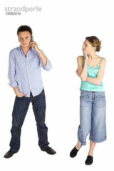 Junges  attraktives  lässiges Paar  Mann telefoniert  besorgte Frau schaut ihn an  vor weißem Hintergrund