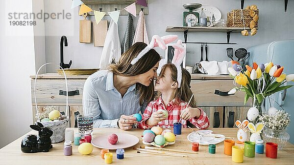 Mädchen Mutter berührt Nasen beim Bemalen Eier Ostern