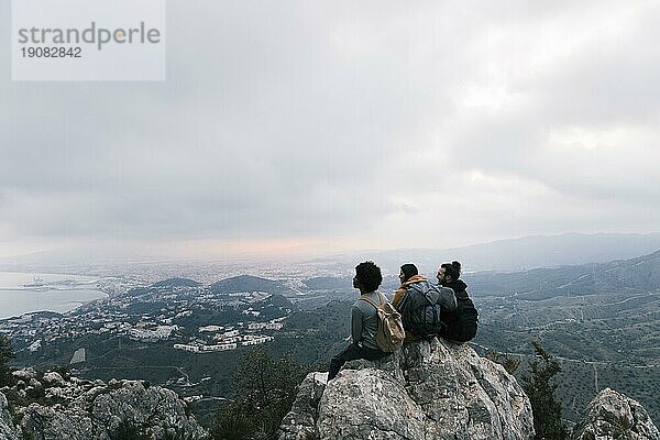 Drei Freunde sitzen oben auf dem Berg und genießen die malerische Aussicht