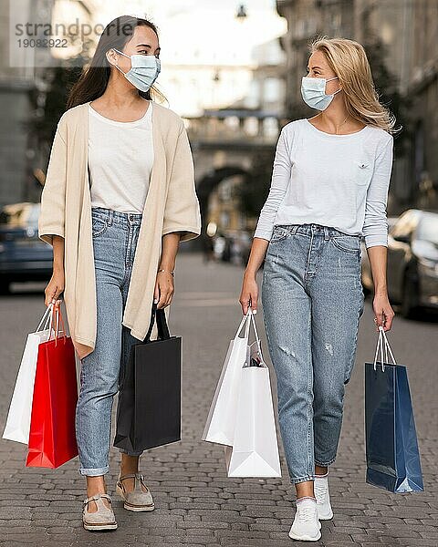 Zwei Freunde mit medizinischen Masken beim Einkaufsbummel