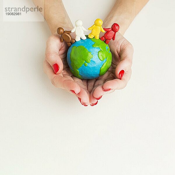 Draufsicht Hände halten Globus mit Menschenfiguren