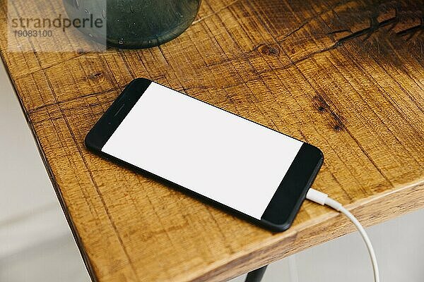 Smartphone mit leeren weißen Bildschirm hölzernen Schreibtisch