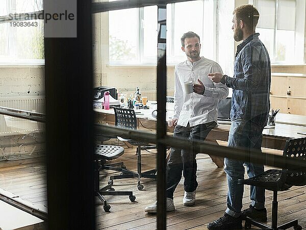 Zwei männliche Geschäftsleute im Gespräch am Arbeitsplatz