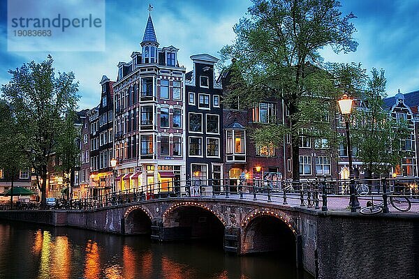 Dämmerung in der Stadt Amsterdam  traditionelle holländische Häuser und Brücke über den Kanal  Ecke Grimburgwal und Oudezijds Voorburgwal  Nordholland  die Niederlande