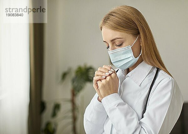 Seitenansicht covid Recovery Center Ärztin mit Stethoskop medizinische Maske beten