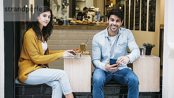 Hispanisches Paar mit elektronischem Gerät im Café