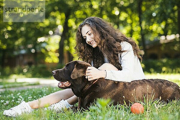 Seitenansicht lächelnde junge Frau streichelt ihren Hund Garten