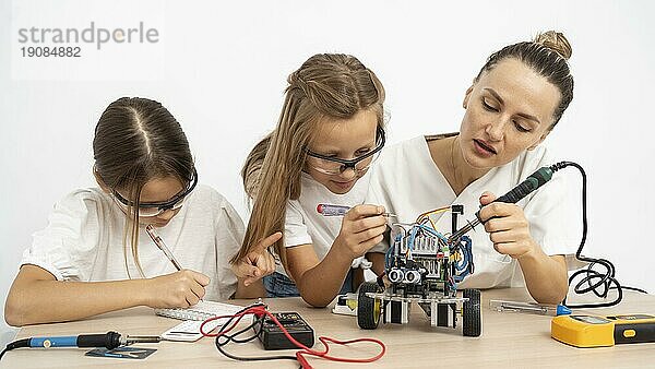 Mädchen weiblichen Lehrer tun Wissenschaft Experimente zusammen mit Roboter Auto
