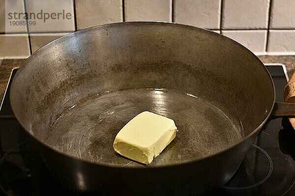 Zubereitung von Dampfnudeln  Butter in rustikaler alter Dampfnudelpfanne  typisch traditionell bayerische Küche  Deutschland  Europa