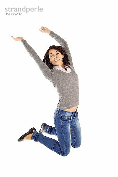 Glückliche freudige junge Frau springen in die Luft vor weißem Hintergrund