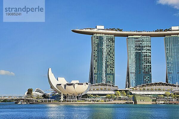 Singapur  25. Februar 2020. Berühmtes Touristenziel  Marina Bay Sands  Shoppes Einkaufszentrum  ArtScience Museum und Helixbrücke in der Marina Bay  an einem sonnigen Tag. Sehenswerte Wahrzeichen des Stadtstaates  klarer blauer Himmel  azurblaues Wasser. Ikonische futuristische Architektur und Symbole  Asien