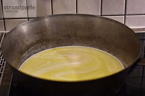 Zubereitung von Dampfnudeln  Butter in rustikaler alter Dampfnudelpfanne  typisch traditionell bayerische Küche  Deutschland  Europa