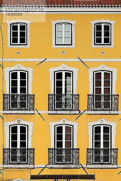 Traditionelles Gebäude mit gelber Fassade und hohen Fenstern mit Balkonen in Lissabon  Portugal  Europa