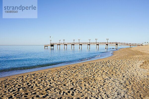 Ruhige Kulisse eines Sandstrandes und eines hölzernen Piers an der Costa del Sol zwischen dem Ferienort Marbella und Puerto Banus in Spanien  Provinz Malaga