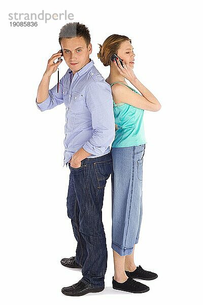 Junges attraktives lässiges Paar  das Rücken an Rücken steht und telefoniert  vor weißem Hintergrund