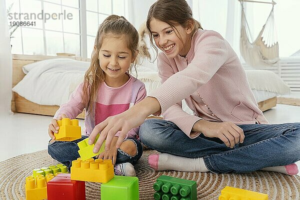 Vorderansicht zwei lächelnde Schwestern spielen mit Spielzeug nach Hause
