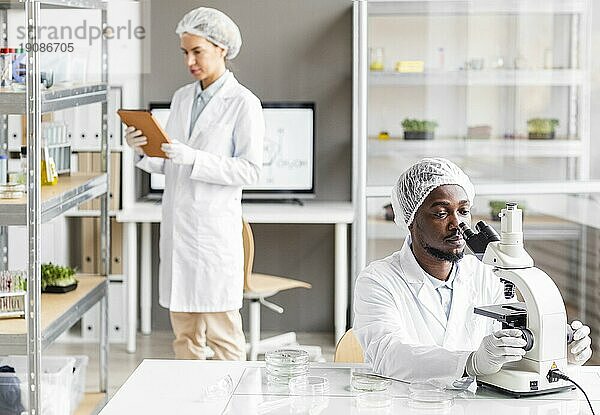 Weibliche männliche Forscher Biotechnologielabor mit Mikroskoptablett