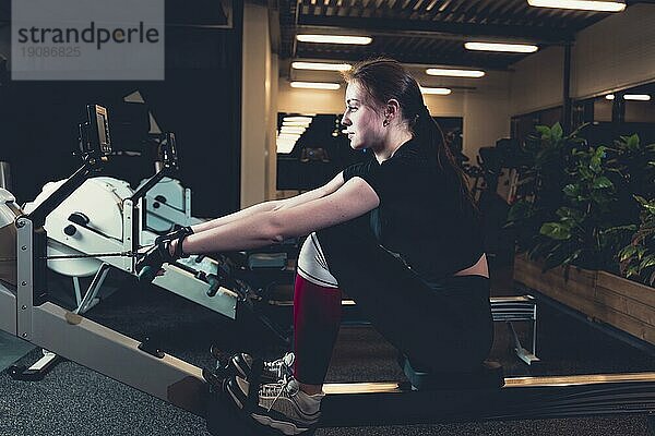 Frau beim Training an der Rudermaschine im Fitnessstudio