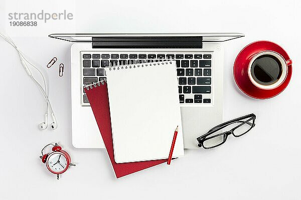 Draufsicht Büromaterial Laptop Kaffeetasse Wecker Brille weißer Schreibtisch