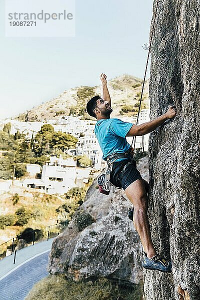 Seitenansicht sportlicher Mann beim Klettern am Fels