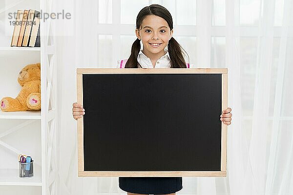 Lächelndes Kind Schuluniform zeigt Tafel Klassenzimmer