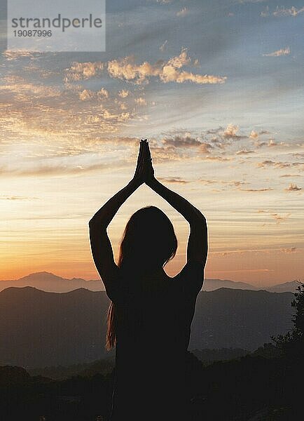 Rückenansicht Frau Yogapose bei Sonnenuntergang