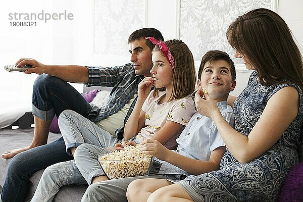 Familie ißt Popcorn  während sie zu Hause fernsieht