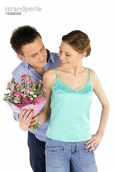 Glückliches  junges  attraktives  verliebtes Paar  Mann schenkt einer Frau Blumen  vor weißem Hintergrund