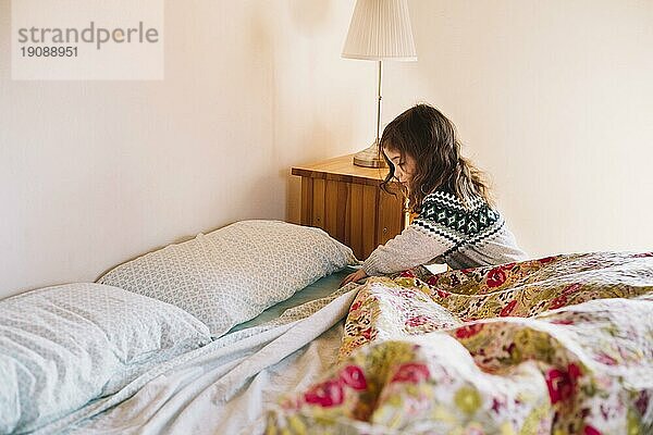 Mädchen ordnet Bettlaken Schlafzimmer