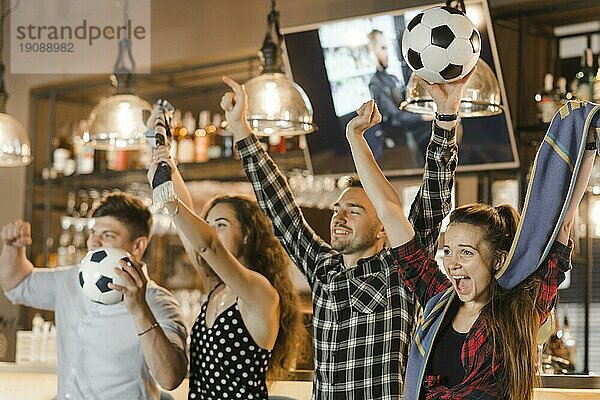 Gruppe von Freunden  die gemeinsam Sport schauen und den Sieg feiern Bar