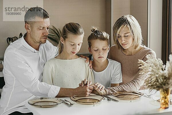 Eine Familie betet und hält dabei ihre Hände zusammen