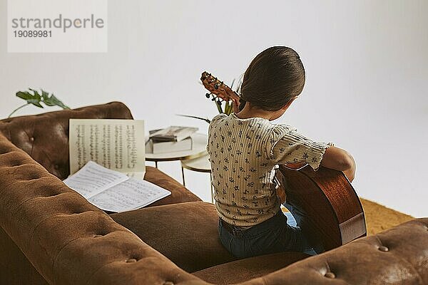 Kleines Mädchen lernt zu Hause Gitarre spielen