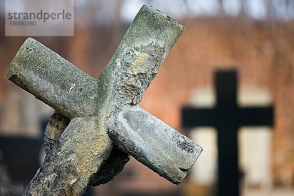 Ein altes schiefes Grabkreuz aus dem 19. Jahrhundert auf einem Friedhof  unscharfer Hintergrund  geringe Tiefenschärfe Komposition