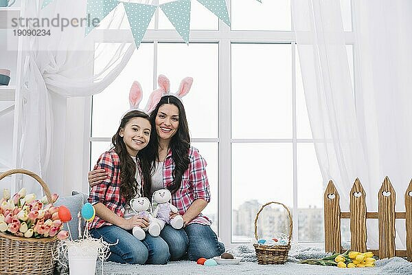 Mutter Tochter sitzt zusammen und hält ausgestopften Hasen Ostern Feier