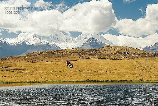 Foto von drei Eingeborenen  die an der Küste spazieren gehen  mit der großen Bergkette Cordillera Negra mit schneebedeckten Gipfeln in der Ferne in Peru  Südamerika