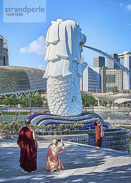 Singapur  25. Februar 2020. Buddhistische Mönche und Nonnen fotografieren den berühmten Merlionbrunnen das Symbol von Singapur  halb Löwe halb Fisch. Esplanade Center und CBD im Hintergrund  Asien