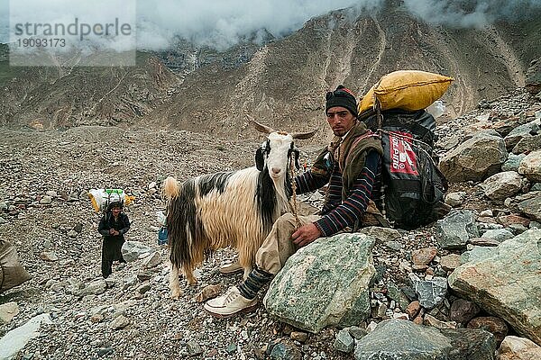 Karakoram  Pakistan  24. Juli 2018: Sherpa mit einer Ziege beim Ausruhen während des Trekkings zum K2 Basislager im Karakoram Gebirge in Pakistan. Illustrativer Leitartikel  Asien