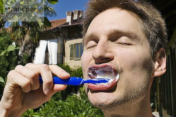 Ein Mann bei der Zahnplege im Freien
