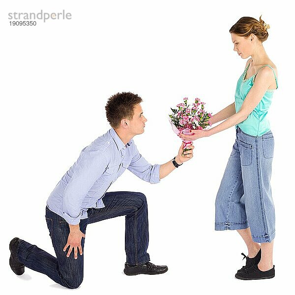 Junger Mann  der seiner Freundin einen Blumenstrauß überreicht  vor weißem Hintergrund