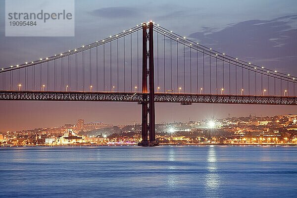 25. April (Portugiesisch: Ponte 25 de Abril) Brücke über den Tejo bei Nacht und die Stadt Lissabon  Portugal im Hintergrund