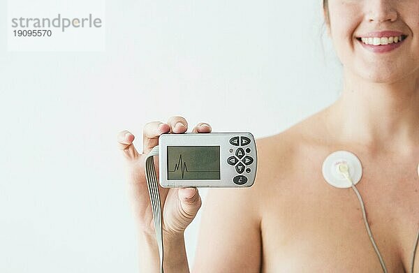 Frau mit Elektroden hält Monitor mit Kardiogramm