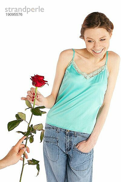 Junge schöne glückliche fröhliche Frau nimmt eine einzelne Rose von einem Mann Hand vor weißem Hintergrund