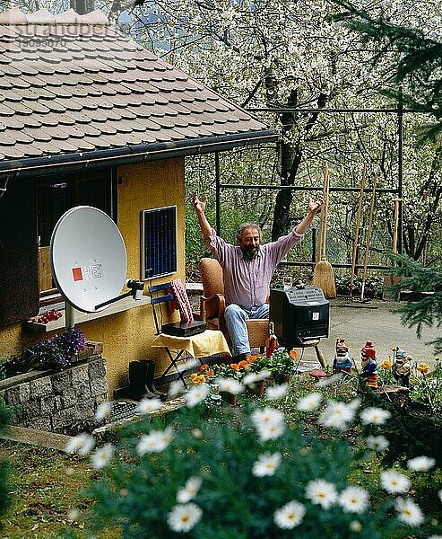 Schrebergaertner beim Fernsehen im Garten mit Satelittenschuessel digital und 6x6 Dia