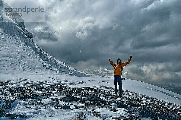 Glückliche junge Bergsteigerin mit ausgebreiteten Armen im Pamirgebirge in Tadschikistan