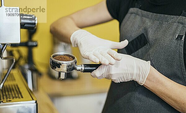 Seitenansicht Barista mit Latexhandschuhen bei der Vorbereitung der Kaffeemaschine