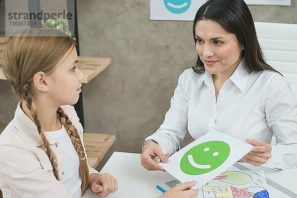 Freundliche junge weibliche Psychologin hält glückliche Emotion Gesicht Karte