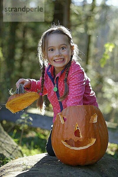 Mädchen spielt mit einem Halloween Kürbis  in der Natur  Kind im Herbst  Oberbayern  Bayern  Deutschland  Europa